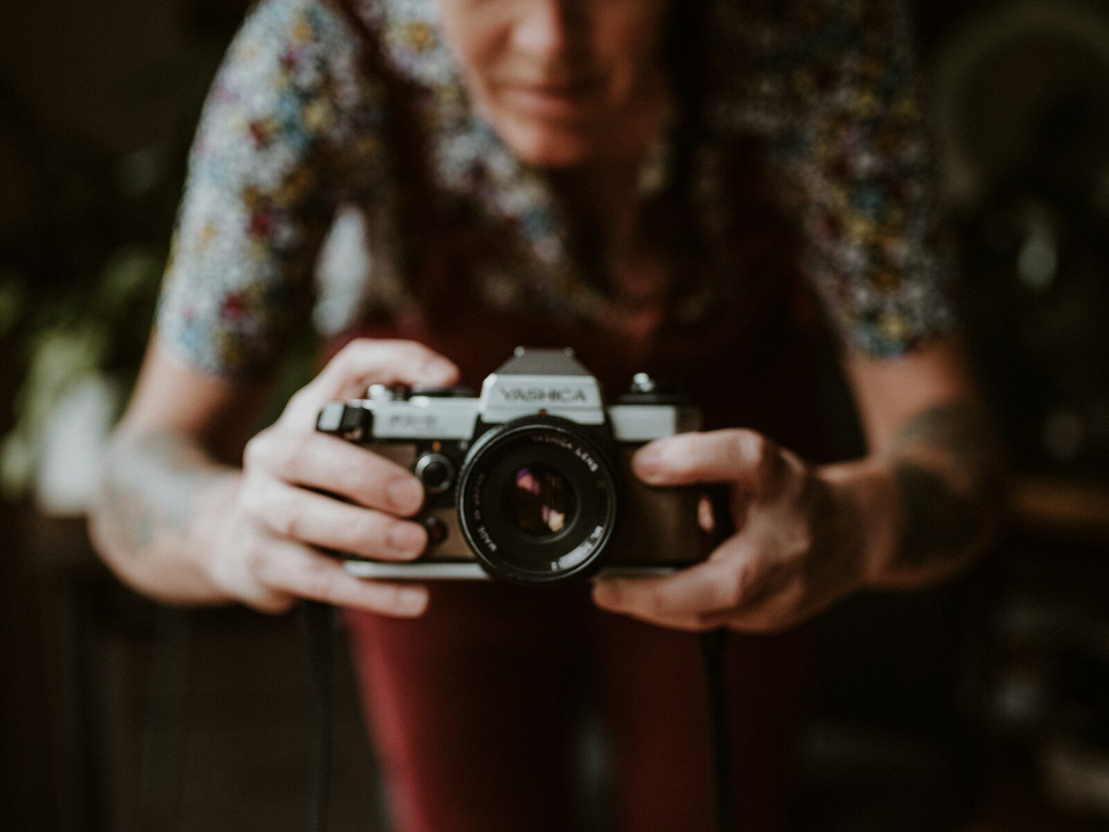 woman in green and white floral shirt holding white and black nikon dslr camera